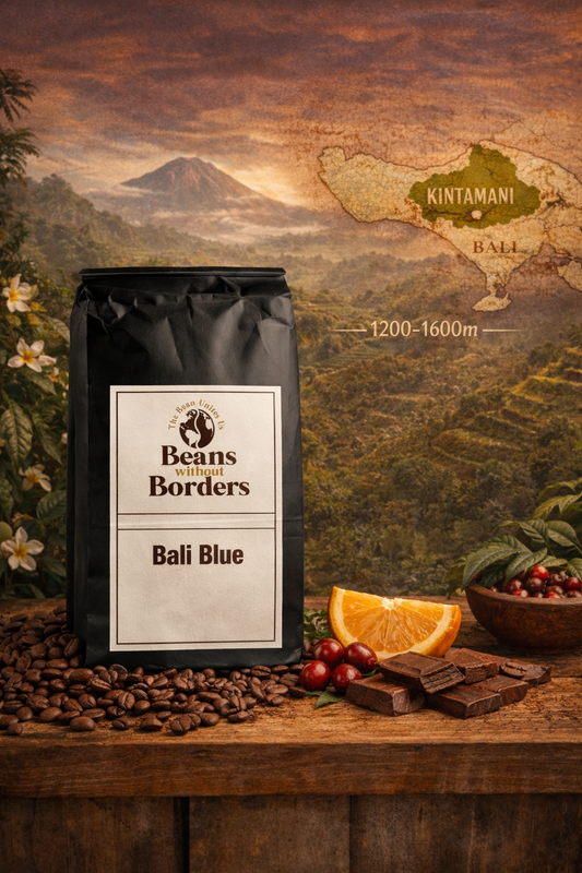 Coffee bag labeled 'Beans Without Borders Bali Blue' on a wooden surface with coffee beans, chocolate, and fruit.